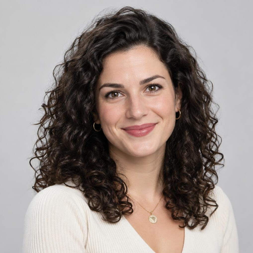 Studio portrait of a young woman with curly hair smiling